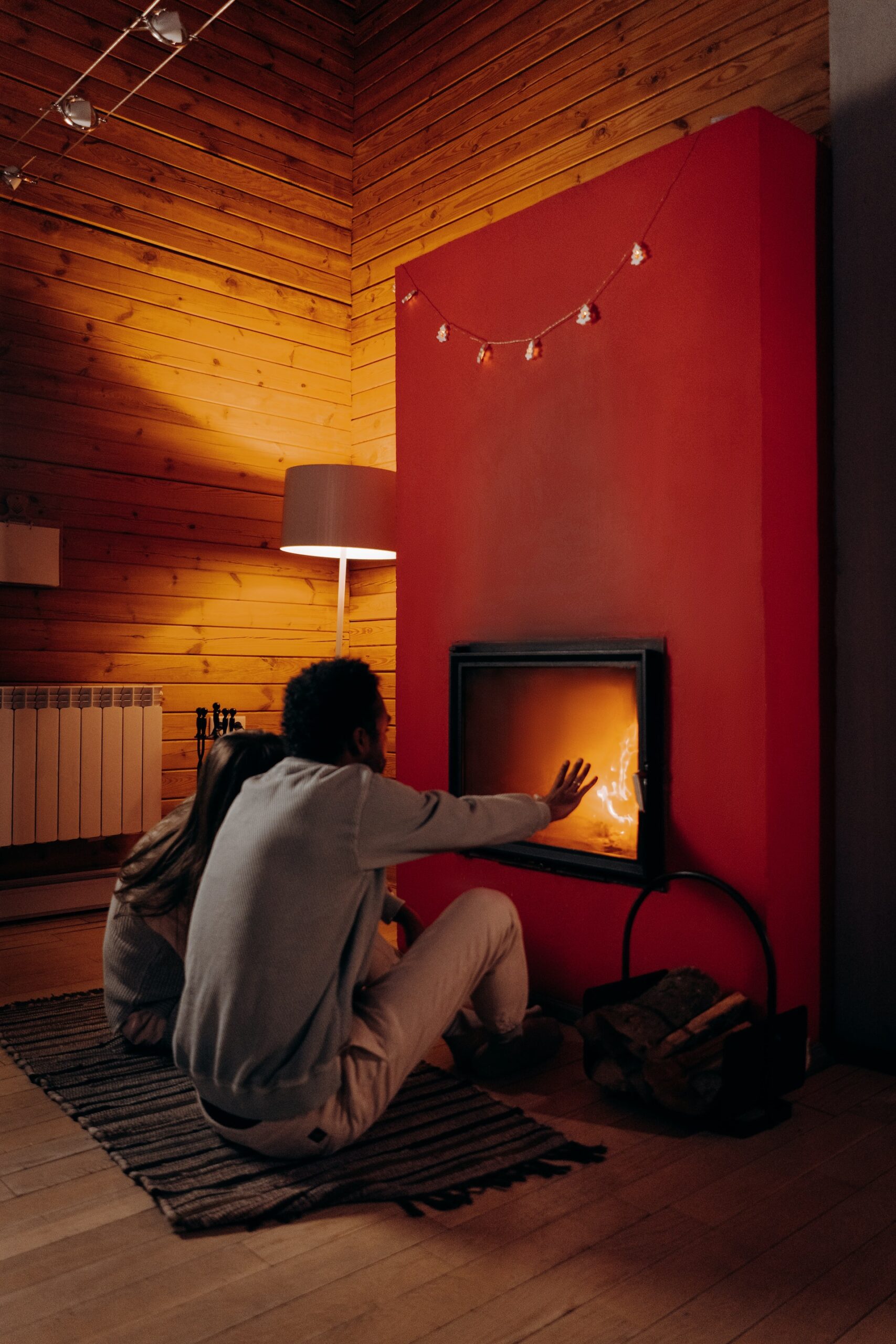 Energy Efficient Rental Properties: This image depicts a couple warming themselves up in front of a fire pit inside their home.